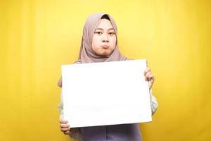 hübsche junge muslimische Frau traurig, Hand hält leeres leeres Banner, Plakat, weiße Tafel, leeres Schild, weiße Werbetafel, präsentiert etwas im Kopierraum, Werbung foto