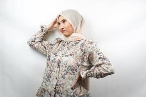 Schöne junge asiatische muslimische Frau gestresst, schwindelig, ein Problem haben, sich deprimiert fühlen, mit den Händen, die den Kopf isoliert auf weißem Hintergrund halten foto