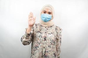 muslimische frau, die medizinische maske mit offenem handzeichen trägt, wie geht es dir, hallo zeichenhand, isoliert auf weißem hintergrund