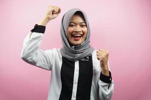 schöne junge asiatische muslimische frau, die selbstbewusst, enthusiastisch und fröhlich mit geballten händen lächelt, zeichen des erfolgs, schlagen, kämpfen, keine angst, einzeln auf rosa hintergrund foto