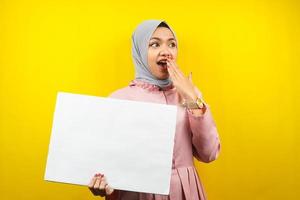 hübsche junge muslimische Frau schockiert, überrascht, wow, Hand, die leeres leeres Banner, Plakat, weiße Tafel, leeres Schild, weiße Werbetafel hält, etwas im Kopierraum präsentiert, Werbung foto