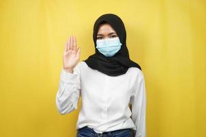 muslimische frau, die medizinische maske mit offenem handzeichen trägt, wie geht es dir, hallo zeichenhand, einzeln auf gelbem hintergrund