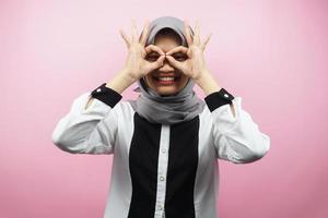 schöne asiatische junge muslimische frau, die fröhlich und aufgeregt lächelt, mit brillenhänden, einzeln auf rosa hintergrund