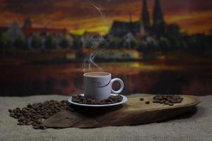 Tasse heißen Kaffee und Kaffeekörner auf Holzuntergrund foto