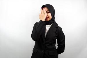 schöne asiatische junge muslimische Geschäftsfrau mit der Hand, die ein Auge bedeckt und in die Kamera schaut, die auf weißem Hintergrund lokalisiert wird foto