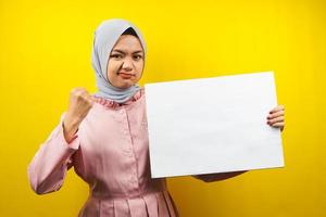 hübsche junge muslimische Frau, die fröhliche leere leere Banner, Plakate, weiße Tafeln, leere Schilder, weiße Werbetafeln hält, etwas im Kopierraum präsentiert, Werbung foto