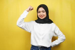 schöne asiatische junge muslimische frau mit angehobenen muskeln, kraftzeichenarme, isoliert auf gelbem hintergrund