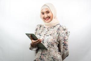 schöne junge asiatische muslimische geschäftsfrau zuversichtlich und lächelnd, mit den händen, die tablette halten, zeit zur arbeit, produktive zeit, isoliert auf weißem hintergrund foto