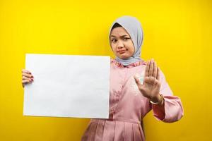 Hübsche junge muslimische Frau, die leere leere Banner, Plakate, weiße Tafeln, leere Schilder, weiße Werbetafeln hält und etwas im Kopierraum präsentiert, Werbung foto