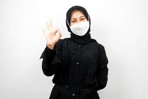 muslimische Frauen mit weißen Masken, Anti-Corona-Virus-Bewegung, Anti-Covid-19-Bewegung, Gesundheitsbewegung mit Masken, mit Händen, die ein gutes Zeichen zeigen, gute Arbeit, Erfolg, Sieg, einzeln auf weißem Hintergrund