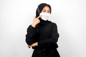 muslimische frau mit weißer maske, mit der hand, die auf maske zeigt, koronavirus-geste verhindern, covid-19 verhindern, isoliert auf weißem hintergrund foto