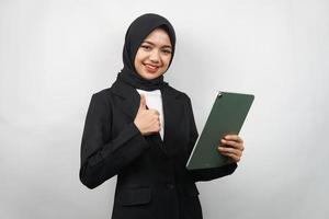 schöne junge asiatische muslimische Geschäftsfrau zuversichtlich und lächelnd, mit den Händen, die Tablette halten, Zeit zum Arbeiten, produktive Zeit, isoliert auf grauem Hintergrund foto
