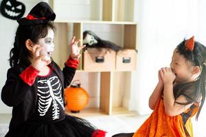 Porträt von zwei Schwestern, die sich beim Halloween-Fest wie ein Geist erschrecken, der sich gegenseitig erschreckt
