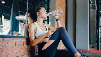 schöne junge asiatische dame übung trinkwasser nach fettverbrennungstraining im fitnesskurs. Sportler mit Sixpack, Sportler-Freizeitaktivität, funktionelles Training, gesundes Lifestyle-Konzept.