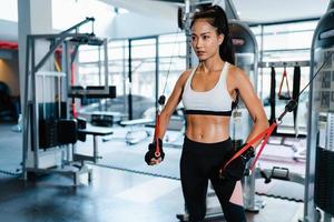 junge asiatische Dame Übung macht Übungsgerät Kabel Crossover Fettverbrennung Workout in Fitness-Klasse. Sportler mit Sixpack, Sportler-Freizeitaktivität, funktionelles Training, gesunder Lebensstil. foto