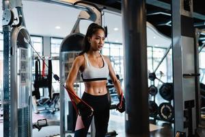 junge asiatische Dame Übung macht Übungsgerät Kabel Crossover Fettverbrennung Workout in Fitness-Klasse. Sportler mit Sixpack, Sportler-Freizeitaktivität, funktionelles Training, gesunder Lebensstil. foto