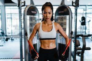 junge asiatische Dame Übung macht Übungsgerät Kabel Crossover Fettverbrennung Workout in Fitness-Klasse. Sportler mit Sixpack, Sportler-Freizeitaktivität, funktionelles Training, gesunder Lebensstil. foto