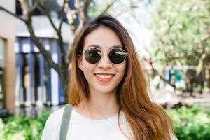 Nahaufnahme einer jungen asiatischen Frau, die im Garten lächelt und ihren Lebensstil in der Stadt am Wochenendmorgen genießt. junge Frau mit ihrem Wochenendstadtlebensstil im Garten. Outdoor-Aktivitäten und City-Lifestyle-Konzept.