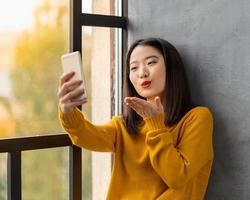 junge asiatische Frau, die selfie nimmt und Kuss bläst. schönes Teenager-Mädchen foto