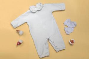 Modell eines weißen Babybodys auf farbigem Hintergrund, Nahaufnahme mit roten Hosen und Gnomenmodell von Kleidung für Neugeborene. mit textfreiraum foto