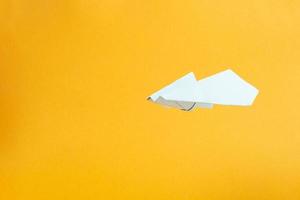 Weißbuchflugzeug fliegt auf gelbem Hintergrund Konzept Flüge und Reisen foto