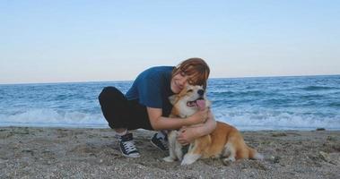 junge Frau spielt mit Corgi-Hund am Meeresstrand foto