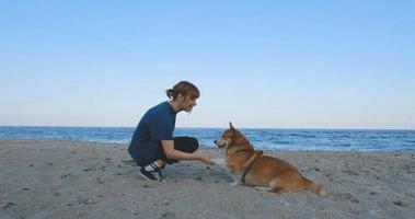 junge Frau spielt mit Corgi-Hund am Meeresstrand foto