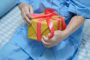 asiatische senior oder ältere alte damenpatientin, die geschenkbox in weihnachts- und neujahrsfeierfestfeiertagsfeier im krankenhaus hält. foto