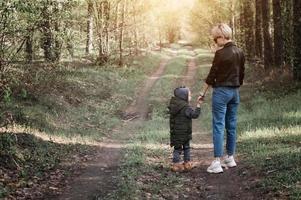 Mutter geht mit ihrem Kind durch den Wald foto