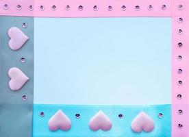 Schablone. Satinbänder in Blau, Grau und Pink mit rosa Herzen und Pailletten auf weißem Hintergrund mit Platz für die Aufschrift. foto