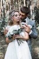 das Brautpaar umarmt sich am Hochzeitstag im Wald. Hochzeitszeremonie. selektiver Fokus. Filmkorn. foto