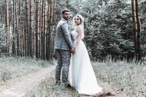 das Brautpaar umarmt sich am Hochzeitstag im Wald. Hochzeitszeremonie. selektiver Fokus. Filmkorn. foto