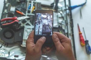 Ein Mann repariert einen Computer, lötet eine Platine, repariert Elektronik und moderne Technologien foto