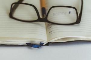 schwarze brille liegt auf dem buch auf dem tisch, ruht sich im bildungsprozess aus foto