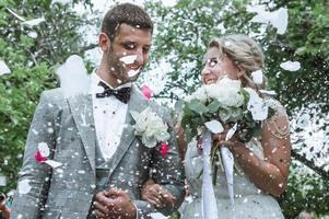 Braut und Bräutigam bei der Hochzeitszeremonie. Gratulation der Gäste. Duschen mit Rosenblättern. selektiver Fokus. Filmkorn. foto