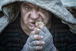 ein obdachloser, zahnloser, hungriger Mann isst gierig ein Stück Brot. Armut, Arbeitslosigkeit, Hunger. Porträt. foto