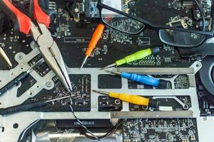 Ein Mann repariert einen Computer, lötet eine Platine, repariert Elektronik und moderne Technologien foto