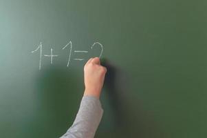 Schülerhand schreibt während des Unterrichts in der Schule mit Kreide auf eine Tafel. foto