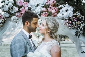 das Brautpaar umarmt sich am Hochzeitstag am Hochzeitsbogen. selektiver Fokus. Filmkorn. foto