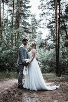 das Brautpaar umarmt sich am Hochzeitstag im Wald. Hochzeitszeremonie. selektiver Fokus. Filmkorn. foto