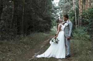 das Brautpaar umarmt sich am Hochzeitstag im Wald. Hochzeitszeremonie. selektiver Fokus. Filmkorn. foto