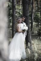 das Brautpaar umarmt sich am Hochzeitstag im Wald. Hochzeitszeremonie. selektiver Fokus. Filmkorn. foto