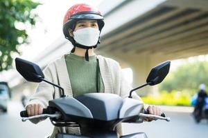 Asiatin mit dem Motorrad auf dem Weg zur Arbeit