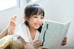 asiatisches Kind liest Buch zu Hause foto