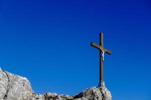 Holzkreuz mit weißer Jesusstatue auf den Felsen am Gipfel mit dunkelblauem Himmel foto
