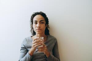 junge schwarze Frau trinkt Wasser während der Zeit zu Hause foto
