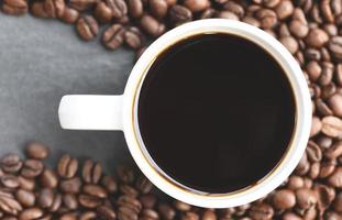 Kaffeetasse auf gerösteten Kaffeebohnen auf dunklem Hintergrund foto