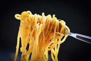 Spaghetti-Gabel auf dunkelschwarzem Hintergrund - traditionelles leckeres Essen leckere appetitliche klassische italienische Spaghetti-Nudeln foto