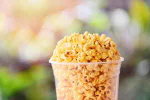 Popcorn in Tasse und Naturgrün und Sonnenlichthintergrund - süße Butter Popcornsalz