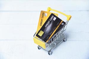 Online-Shopping mit Kreditkarte in einem Warenkorb auf dem Holzhintergrund für die Online-Zahlung zu Hause